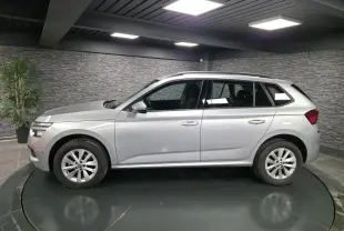 Vue latérale droite d’un Skoda Kamiq gris métallisé 2023, avec jantes alliage 16 pouces et barres de toit noires.