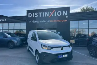 Vue 3/4 avant droite du Citroën Berlingo blanc Icy avec calandre noire et jantes tôle grises, devant un bâtiment Distinxion.