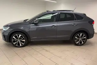Volkswagen Taigo gris cendré vue de profil côté gauche, avec jantes noires brillantes et toit ouvrant électrique.