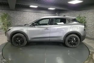 Vue de profil côté gauche d'une Alfa Romeo Junior 1.2 Ibrida grise avec jantes alliage noires dans un showroom.