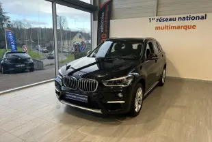 BMW X1 F48 Saphirschwarz en 3/4 avant droit, SUV compact diesel exposé en showroom lumineux.