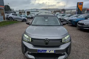 Vue avant d'un Citroën C3 Aircross gris métallisé avec toit noir et phares LED allumés sous la pluie.