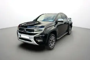 Volkswagen Amarok V6 noir en 3/4 avant droit, avec jantes alu 21 pouces et barres de toit visibles.