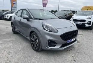 Ford Puma gris Solar vu en 3/4 avant droit sur un parking, avec calandre noire et jantes bicolores.