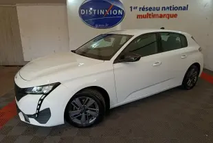 Peugeot 308 blanche vue en 3/4 avant droit, avec phares LED et jantes alliage foncé dans un showroom.