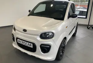 Microcar Dué Must DCI blanc nacré en 3/4 avant droit, avec jantes noires bicolores et calandre marquée.