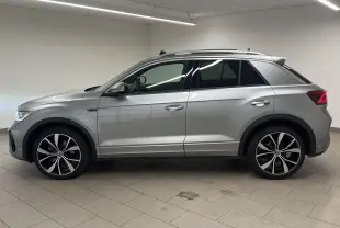 Profil côté gauche du Volkswagen T-Roc gris pyrite 2024 avec jantes 19 pouces et toit ouvrant panoramique.