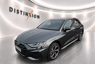 Audi A3 Sportback gris Daytona vue 3/4 avant droit dans un showroom lumineux avec logo Distinxion en arrière-plan.