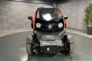 Vue frontale d'une Renault Twizy Intens 2019 orange avec logo Renault et phares ronds dans un showroom.