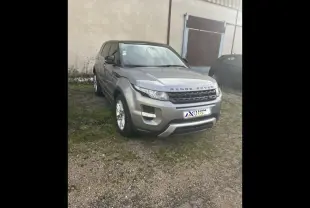 Range Rover Evoque gris Orkney vu en 3/4 avant droit, stationné devant un bâtiment industriel.
