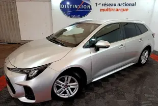 Suzuki Swace gris clair vue 3/4 avant droit en intérieur avec jantes alliage et vitres teintées.